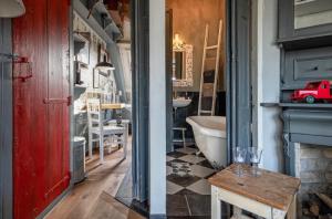 a bathroom with a red door and a table and a tub at Smederij Texel in De Cocksdorp