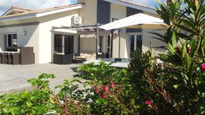 uma casa com um pátio com guarda-sóis e plantas em Villa de 5 chambres avec piscine privee jacuzzi et wifi a Ares a 1 km de la plage em Arès