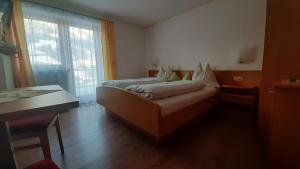 1 dormitorio con cama, mesa y ventana en Landhaus Sonnrain, en Saalbach Hinterglemm