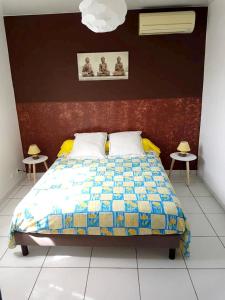 a bedroom with a bed with a colorful quilt and two tables at Maison charmante à Petit-Bourg + Jardin in Petit-Bourg