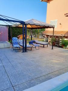 a picnic shelter with two blue chairs and a swing at One bedroom villa with shared pool and enclosed garden at Augusta 8 km away from the beach in Augusta