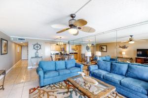 a living room with blue couches and a ceiling fan at Island Echos 7th Floor Condos in Fort Walton Beach