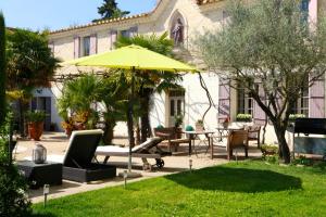 un patio avec un parasol, des chaises et une table dans l'établissement Villa spacieuse et charmante à Saint-Gilles avec piscine privée, à Saint-Gilles