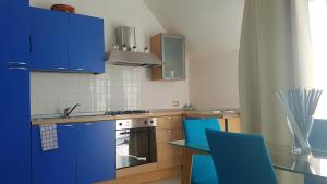 a kitchen with blue cabinets and a table with blue chairs at Comfortable studio in Desenzano del Garda 47 m² with private balcony in Desenzano del Garda +15 photos