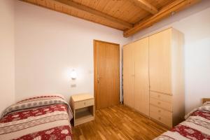 a bedroom with two beds and a wooden ceiling at Villa Mazzel with balcony in Vigo di Fassa