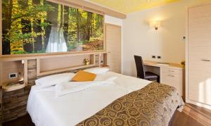 una camera con un letto bianco e una finestra di Family Hotel Serena ad Andalo