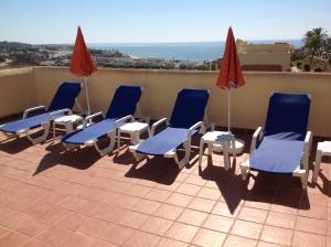 een groep stoelen en parasols op een dak bij Penthouse sea views roof terrace communal pool in La Cala de Mijas