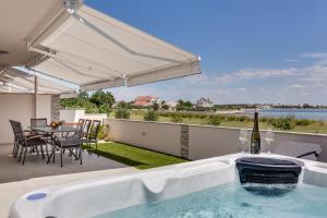 a hot tub on a patio with a table and chairs at Beachfront villas with hot tubs Sun Garden in Privlaka