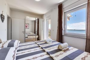 two beds in a bedroom with a large window at Beachfront villas with hot tubs Sun Garden in Privlaka