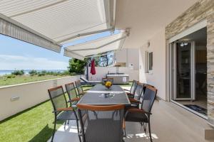 a dining room with a table and chairs and a balcony at Beachfront villas Sun Garden by Adex Travel in Privlaka
