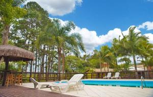 um resort com piscina, cadeiras e árvores em Pousada Villa Da Guarda em Guarda do Embaú