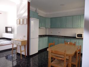 eine Küche mit grünen Schränken, einem Tisch und einem Kühlschrank in der Unterkunft Toni's in Arinaga