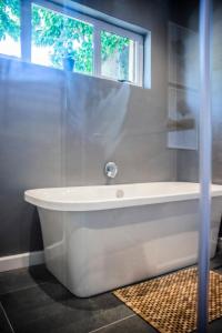 a white bath tub in a bathroom with a window at Seven on Flora- Hot Tub, Modern with amazing outside area in Hermanus