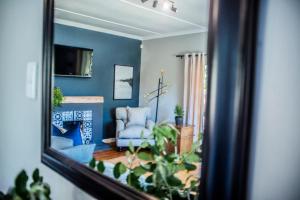a mirror reflecting a living room with a blue wall at Seven on Flora- Hot Tub, Modern with amazing outside area in Hermanus