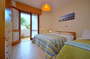 a bedroom with two beds and a sliding glass door at Villa Lucia in Lignano Sabbiadoro
