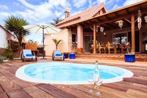 een zwembad met stoelen en een parasol en een huis bij Villa Hibiscus Centrum Corralejo Beach Private Pool Family in Corralejo +44 foto's