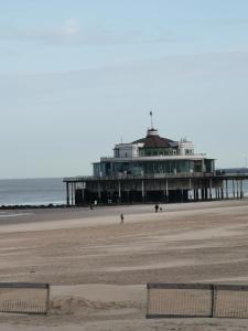 a pier on the beach with people walking on the beach at studionusi in Blankenberge