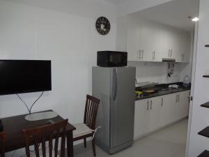 a kitchen with a refrigerator and a table and a dining room at manila sea view homes 21 in Manila
