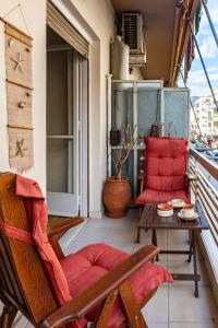 a balcony with a red chair and a table at Dancing on Sunshine - Melina's City Getaway in Kalamata