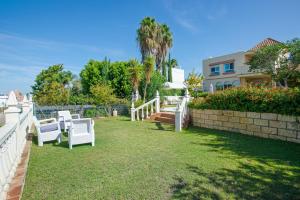 a yard with two white chairs and a fence at 4 bedrooms villa with sea view private pool and furnished terrace at Sanlucar de Barrameda 2 km away from the beach in Sanlúcar de Barrameda