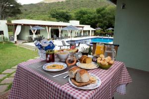 uma mesa com comida de pequeno-almoço numa mesa com piscina em Pousada Cantuá em Serra do Cipó