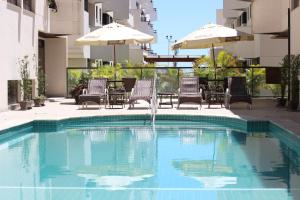 a swimming pool with chairs and umbrellas next to a building at Paraíso Palace Hotel II e III in Florianópolis