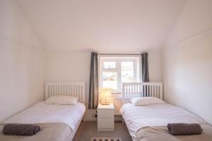 two twin beds in a room with a window at Avocet House in Wells next the Sea