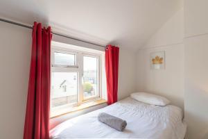 a bedroom with a bed and a window with red curtains at Avocet House in Wells next the Sea