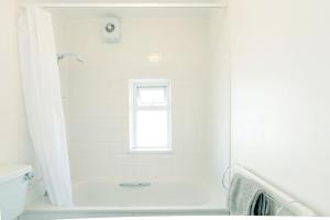 a white bathroom with a tub and a window at Avocet House in Wells next the Sea