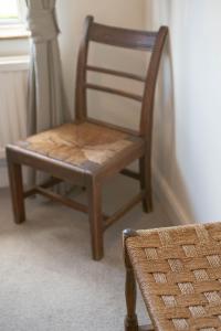 a wooden chair sitting in front of a window at Avocet House in Wells next the Sea