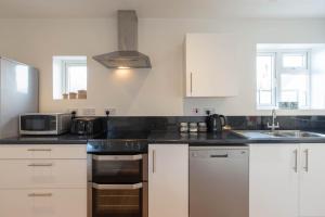 a kitchen with white cabinets and black counter tops at Avocet House in Wells next the Sea
