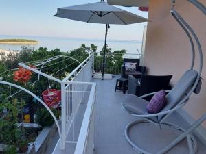 un balcón con una silla y una sombrilla y el océano en Apartmani Vesna Miliša, en Primošten