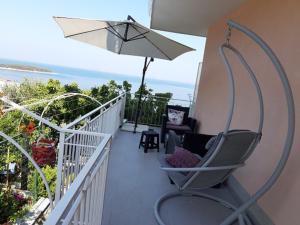 a balcony with a chair and an umbrella at Apartmani Vesna Miliša in Primošten