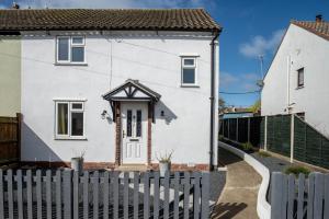 a white house with a fence in front of it at Avocet House in Wells next the Sea