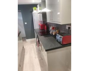 a kitchen with white cabinets and a red appliance at Townhouse @ Nicholls Street Stoke in Stoke on Trent