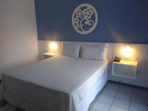 a bedroom with a large white bed with two lights at Joaquina Beach Hotel in Florianópolis +80 photos