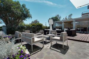 a patio with white chairs and a table and avisor at Hotel Souvenir in Cervia
