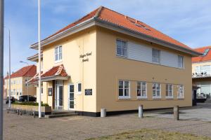 un bâtiment jaune avec un toit rouge dans l'établissement Skagen Hotel Annex, à Skagen