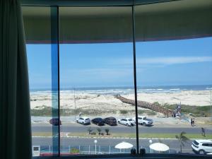 una ventana con vistas a un aparcamiento y al océano en De Rose Praia Hotel, en Torres