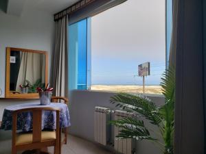 Habitación con mesa y ventana con vistas al océano. en De Rose Praia Hotel en Torres