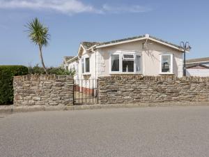 a white house with a stone wall and a palm tree at Summer Breeze in Padstow