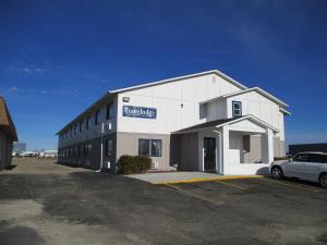 a white building with a car parked in front of it at Travelodge by Wyndham Redwood Falls in Redwood Falls