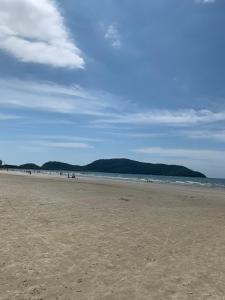 une plage avec des personnes assises sur le sable dans l'établissement Pousada Bertimar, à Bertioga