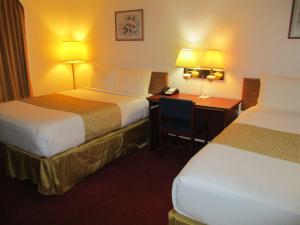 a hotel room with two beds and a desk with a phone at Travelodge by Wyndham Redwood Falls in Redwood Falls