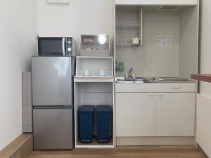 a small kitchen with a refrigerator and a sink at NEW Open かりゆしハウスコザ 本島中部の沖縄市パークアベニュー近くのレトロな街で快適ステイ in Okinawa City