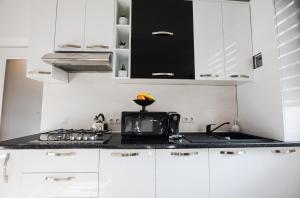 Una cocina con gabinetes blancos y una encimera negra. en White Spacious Apartment, en Sibiu