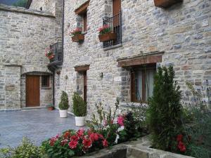 ein Steingebäude mit Blumen und Pflanzen davor in der Unterkunft Hotel Villa Russell in Torla-Ordesa