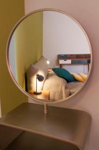 a mirror on a shelf with a bed and a lamp at Retrò B&B in Pisa