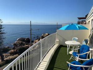a balcony with a table and chairs and an umbrella at Paradise On the Bay in Fish hoek