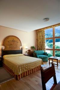 a bedroom with a bed and a couch and a window at Parador de Fuente Dé in Fuente Dé